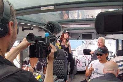Image of one of The Farmer's Cup judges doing an interview in the back of a van with a camera.