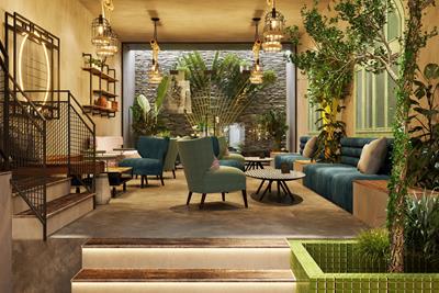 The inside of a classy establishment with blue chairs and couches beside different green house plants of the palm family, all with a warm hue from the lighting