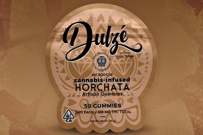 A cannabis edible package that is golden brown with a soft watermark of a Mexican sugar skull in the background, with Dulze written in cursive and the flavor announced as horchata